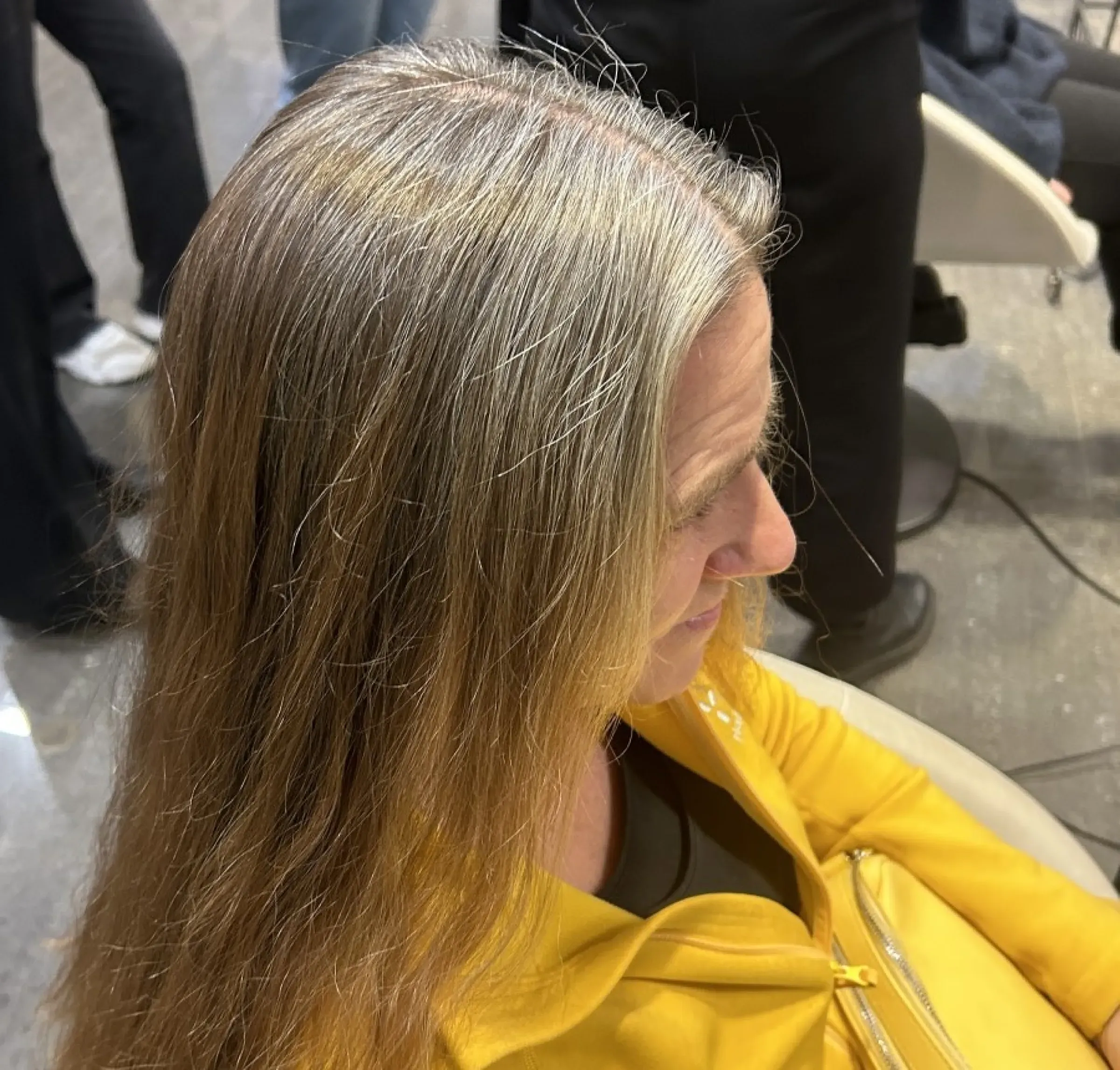 Kund i salongsstol med långt grå-blont hår